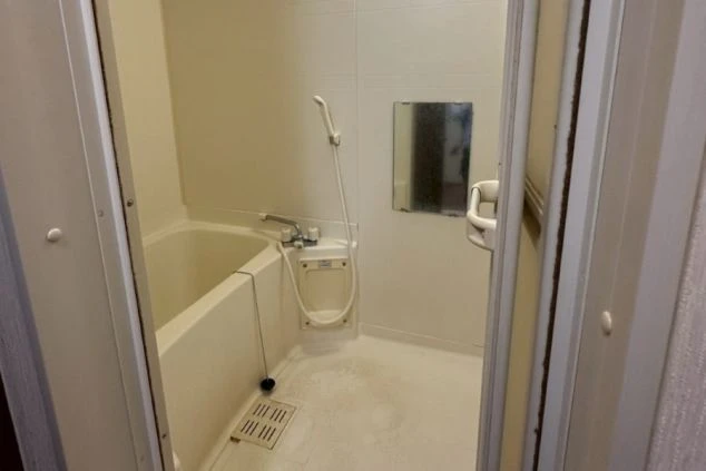 リゾートバイトの寮のバスルームの画像。白い浴槽とシャワーが備え付けられており、鏡が設置されている。リゾートバイトの寮の風呂場の画像。