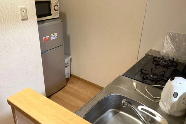 リゾートバイトの寮のキッチンの画像。シンクの隣にガスコンロと電気ケトルが置かれ、奥には冷蔵庫と電子レンジが見える。リゾートバイトの寮の設備の画像。