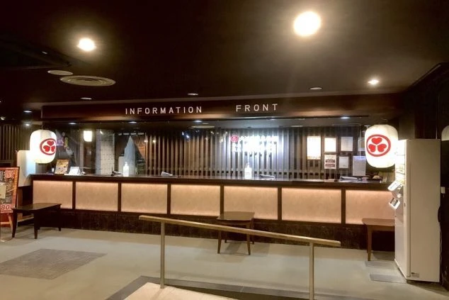 木目調のカウンターが広がる、和風で落ち着いた雰囲気のホテルのフロントが写っている画像。リゾートバイトでホテルや旅館のフロントスタッフとして働くイメージ。