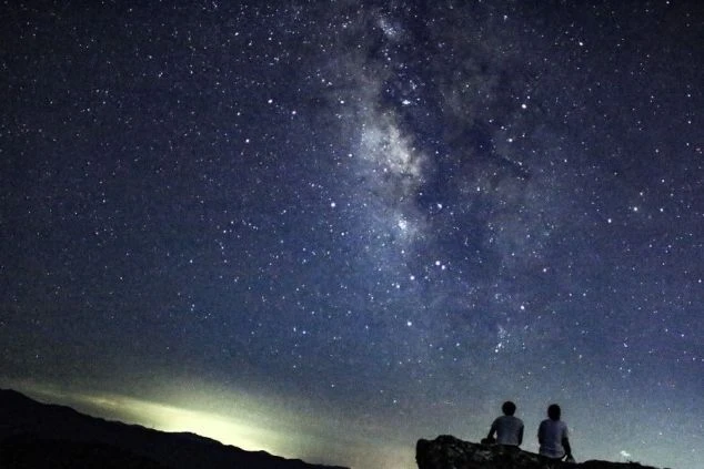 満天の星空の下、二人が並んで天の川を眺めるイメージ画像。リゾートバイトの休日を満喫。