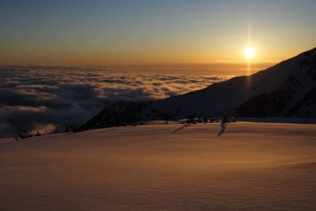 雪山の夕焼け。雲海と地平線に沈む太陽が輝く絶景のイメージ画像。リゾートバイトの休日を満喫。