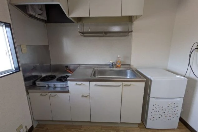 リゾートバイトのシェア寮に備え付けられた共用キッチン。ガスコンロと冷蔵庫があり、自炊が可能です。食費を節約したい方におすすめの自炊可寮付きリゾートバイト。