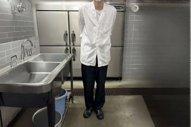 厨房で働く男性の制服。白衣に黒ズボンを着用する、動きやすい服装。
