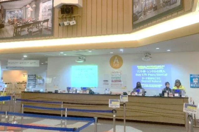 リフト券やレンタル受付カウンターで、複数のスタッフが顧客対応をしている画像。「リフト券・レンタルの購入」などの表示が見えるスキー場のチケット販売業務のイメージ。