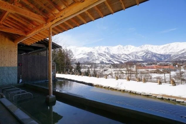 雪景色と雪山を一望できる温泉旅館の露天風呂の画像。温泉に入れる特典付きのリゾートバイトのイメージ。