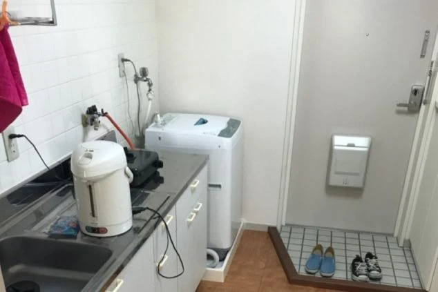 寮のミニキッチンの画像。ガスコンロ、シンク、洗濯機が見える。