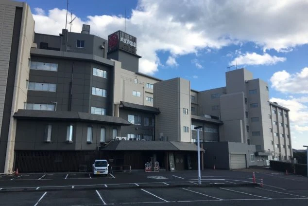 グレーとベージュの外壁を持つ大きな建物の全景。