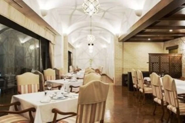 リゾートホテルの豪華なレストラン。白テーブルクロスが敷かれた席と、アーチ型天井が映る職場のイメージ画像。