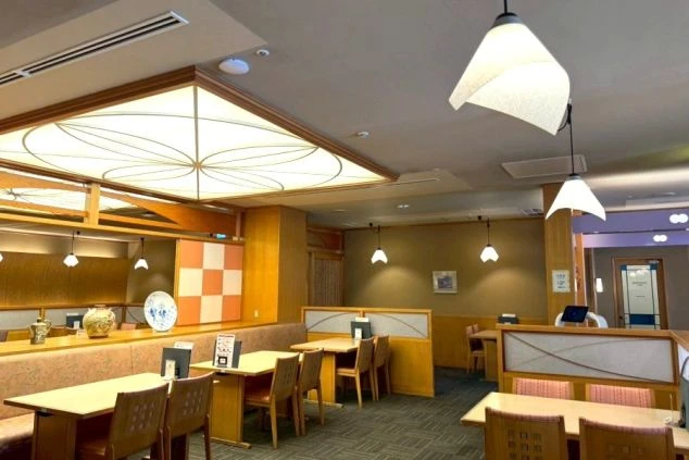 志摩スペイン村内にある日本料理レストラン「的矢」の店内。和の意匠を凝らした照明や格子、落ち着いた色調のテーブル席が並ぶ、清潔感のある和モダンな空間です。