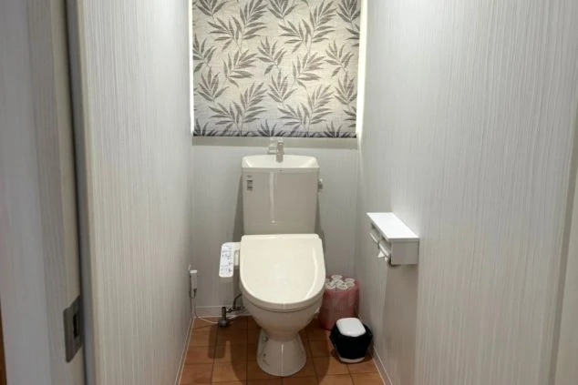 寮のトイレ。温水洗浄便座と窓のロールスクリーンが映る。