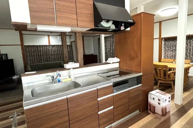 寮のキッチン。木製キャビネットと調理台、レンジフードが映る。