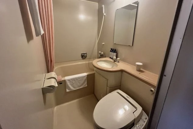 リゾートバイトの客室寮のユニットバスの画像。ピンク色のバスタブとウォシュレット付きのトイレ、洗面台が一体となっている。リゾートバイトの寮の風呂場の画像。