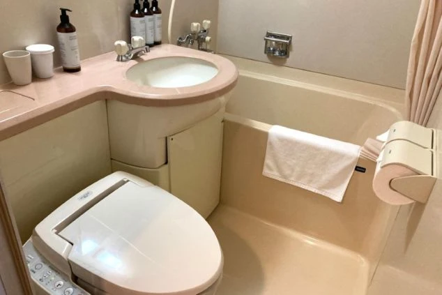 リゾートバイトの客室寮のユニットバスの画像。ピンク色のバスタブとウォシュレット付きのトイレ、洗面台が一体となっている。リゾートバイトの寮の風呂場の画像。