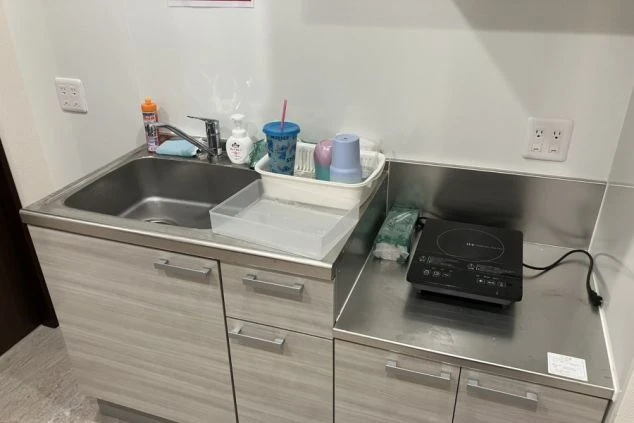 リゾートバイトの社員寮にある共用キッチンのイメージ画像。IHコンロとシンク、調理器具などが写っている。