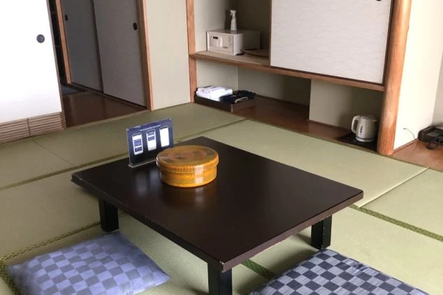 和室のアップ。座卓の上に茶びつがあり、背景の棚には金庫や電気ケトル、浴衣が備え付けられている。