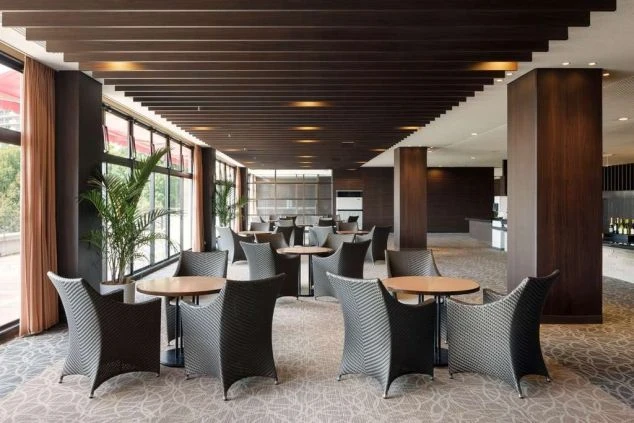 広々としたホテルのラウンジ。窓から光が差し込み、モダンなテーブルと椅子が並んでいる。