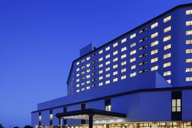 濃い青色の空の下、窓に明かりが灯るホテル。夜のリゾート感を演出する美しい外観。