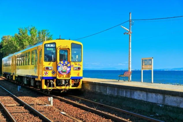 長崎県雲仙温泉エリアの「島原鉄道」の晴れた日の黄色い電車と海の画像