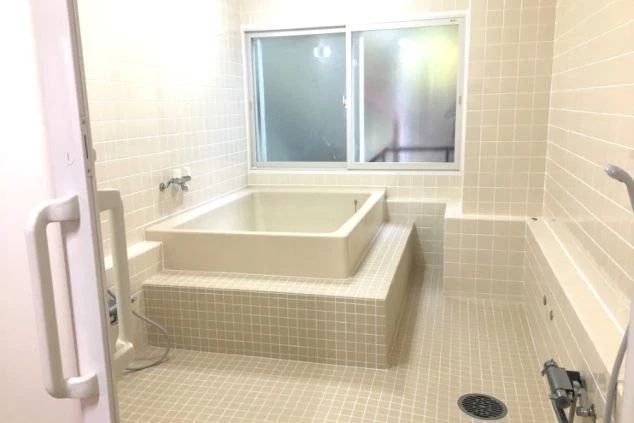 広々とした清潔感のある共同浴場の画像です。白いタイル貼りの大きな浴槽があり、リゾートバイトの寮でゆったりと疲れを癒せるイメージです。