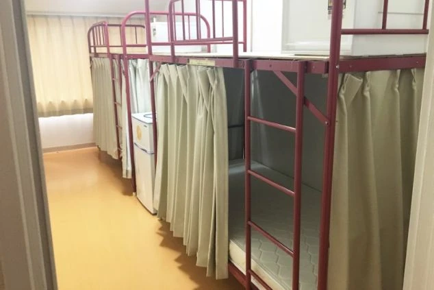 赤色の二段ベッドが複数並んだスキー場の相部屋寮の画像。各ベッドにはプライバシーを守るためのカーテンがついており、リゾートバイトで共同生活が快適に送れます