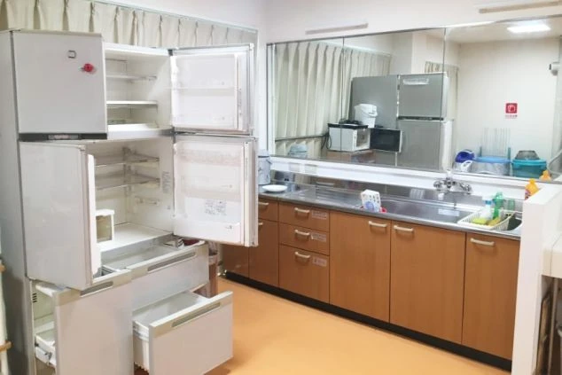 リゾートバイトの寮の共同キッチンの画像。大きな冷蔵庫やシンク、調理台があり、鏡が設置されています。リゾートバイトの寮で自炊ができる共有キッチンのイメージ