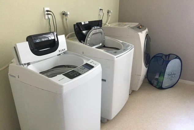 リゾートバイトの寮のト寮のランドリー。複数の洗濯機が並び、洗濯カゴが置かれた清潔な空間が映る。イレのイメージ画像