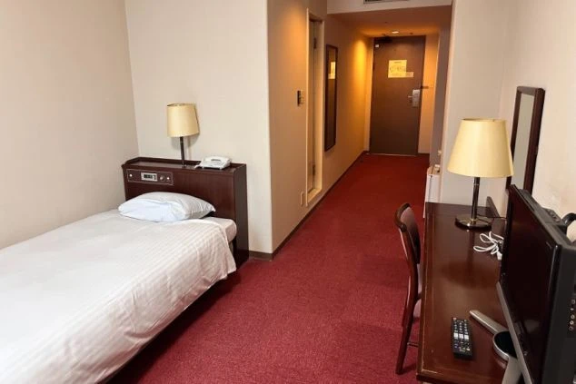 リゾートバイトの客室寮の室内。シングルベッド、デスク、テレビが完備されており、ビジネスホテル感覚で快適に過ごせます。家具家電付きの個室寮で働きたい方におすすめ。