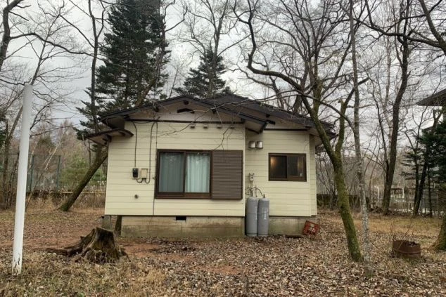 自然に囲まれたコテージ風の寮の外観の画像。平屋建ての建物で、周囲には木々が立ち、静かな環境が特徴。