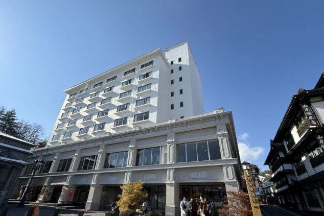 青空に映える真っ白で巨大なホテルの外観。歴史ある街並みに佇む、リゾートバイトの拠点となる大規模宿泊施設。