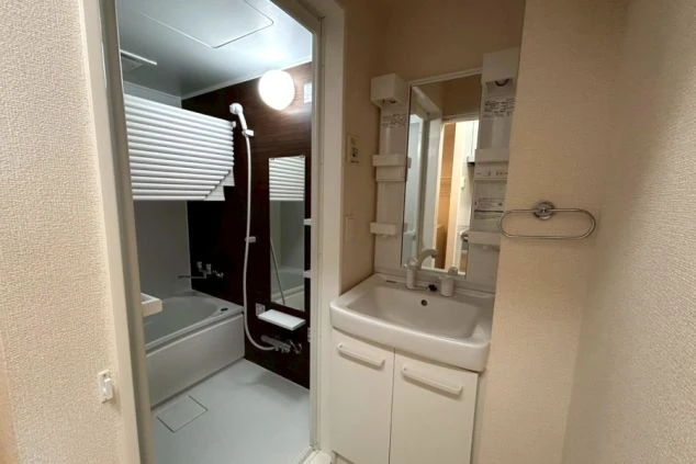 リゾートバイトの寮の洗面所を撮影した画像。鏡と洗面台が備え付けられており、奥にはユニットバスが見える。リゾートバイトの寮の洗面所の画像。