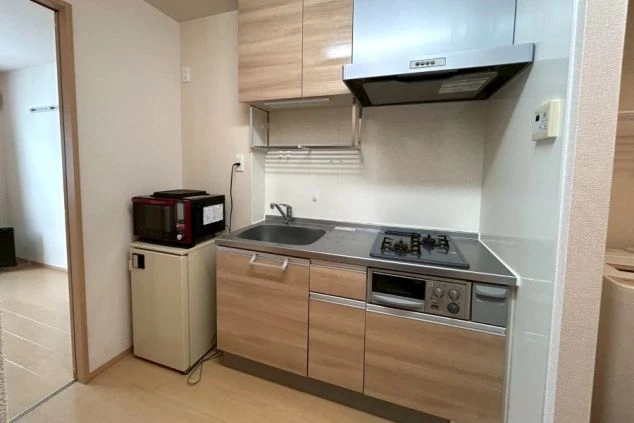 リゾートバイトの寮のキッチンを撮影した画像。冷蔵庫と電子レンジ、ガスコンロが備え付けられており、自炊ができる。リゾートバイトの寮の共用キッチンの画像。