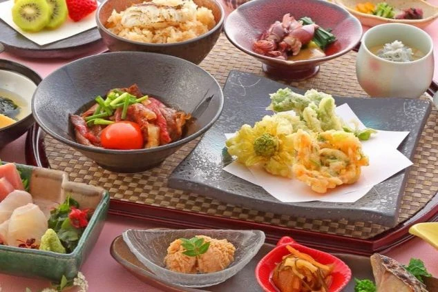 彩り豊かで美味しそうな和食御膳。刺身、天ぷら、肉料理などがバランス良く並べられ、リゾートバイトのまかないや、旅館・ホテルでの調理補助、レストランサービス業務に興味がある方に魅力的な画像。