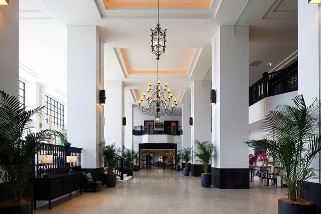 広々とした豪華なホテルのロビーとフロントエリア。シャンデリアが印象的な空間で、リゾートバイトでホテルのフロントやベルスタッフとしてお客様をお迎えする仕事のイメージが伝わる画像。