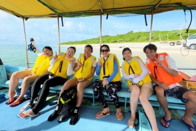 ライフジャケットを着用し、船の上で笑顔を見せるリゾートバイト仲間たち。マリンアクティビティ施設やダイビングショップでのリゾートバイトで、海での仕事と遊びを満喫できる様子が伝わる画像。