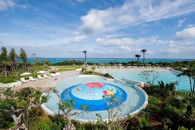 広々としたリゾートホテルの屋外プールと、その奥に広がるエメラルドグリーンの海。プール監視員やホテルのサービススタッフとして、美しい景色の中で働けるリゾートバイトのイメージが伝わる画像。