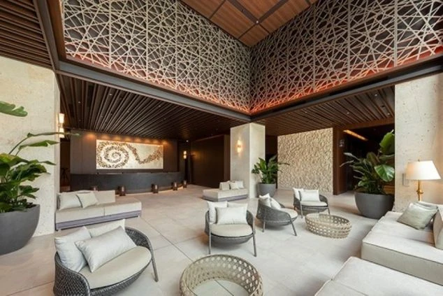 沖縄のリゾートホテルの豪華なロビーとフロントカウンター。モダンなデザインと開放的な空間が特徴で、リゾートバイトでホテルのフロント、ベルスタッフ、またはコンシェルジュとして働きたい方に訴求する画像。