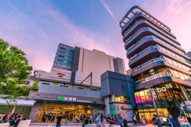 夕焼け空の下、多くの人々で賑わうJR大塚駅前の夜景の画像。駅ビルや商業施設がライトアップされています。職場の最寄り駅のイメージ