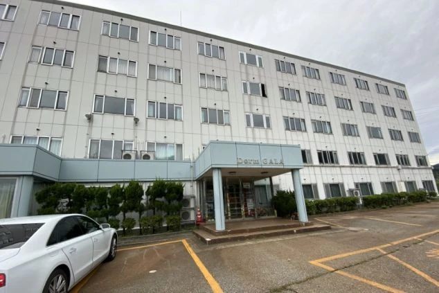 寮の外観。駐車場付きの大きな建物が映る。