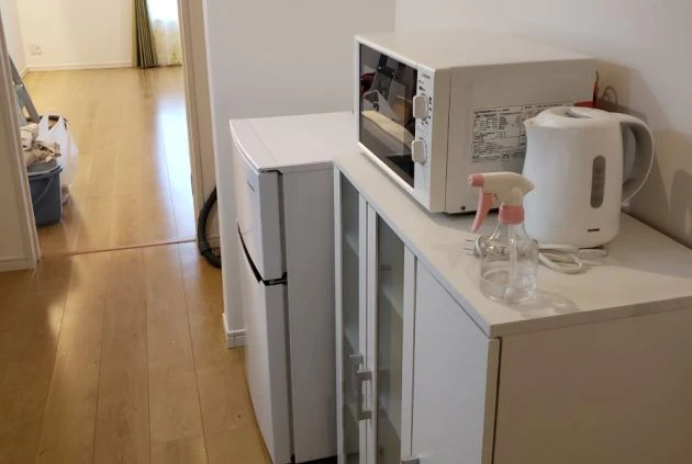 リゾートバイトの完全個室寮の家具家電の画像。電子レンジ・冷蔵庫・食器棚が見える。