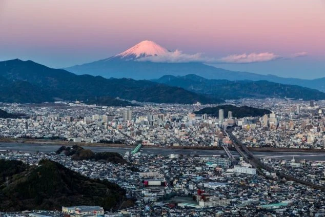富士山を望む市街地の夜景。手前に街の光、奥に雪を被った富士山が映る絶景のイメージ画像。リゾートバイトで暮らす街。