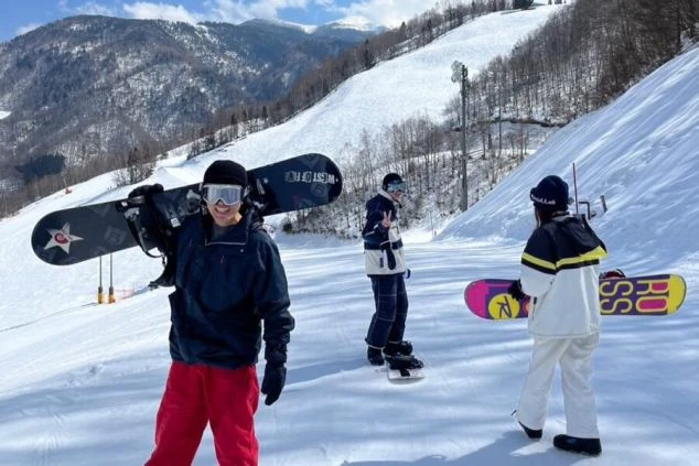 スノーボードを肩に担ぎ、笑顔でゲレンデに立つ若者たち。新潟のスキー場でリゾートバイトをしながらウィンタースポーツを楽しめる、冬の思い出作りに最適なワクトリオリジナル画像。