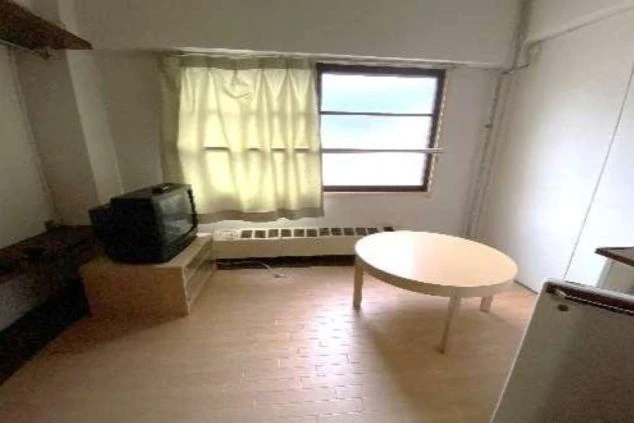 リゾートバイトの個室寮の室内。テレビとローテーブル、窓があり、リラックスして過ごせる空間の寮の部屋の画像。