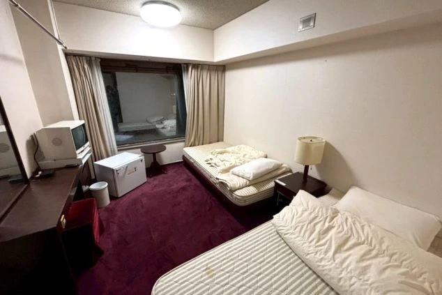 リゾートバイトの女子寮の写真。ベッド2台、テレビ、冷蔵庫、ランプ付きで快適なプライベート空間。