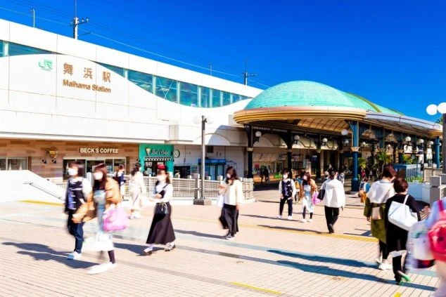 JR舞浜駅の駅舎と、駅前を行き交う多くの人々。東京ディズニーリゾートへの玄関口として、テーマパークやホテルでのリゾートバイトに興味がある方にアクセスと賑わいを伝える画像。