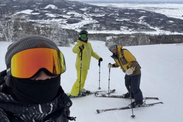 ワクトリでリゾートバイトをしたスタッフが撮影した、雪山でスキーを楽しむ3人の仲間が自撮りをするイメージ画像。広大なスキー場と雪山が映る。リゾートバイトの休日を満喫。