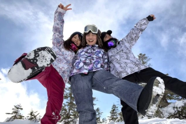 ワクトリでリゾートバイトをしたスタッフが撮影した、雪山でスキーを楽しむ3人の仲間が自撮りをするイメージ画像。広大なスキー場と雪山が映る。リゾートバイトの休日を満喫。