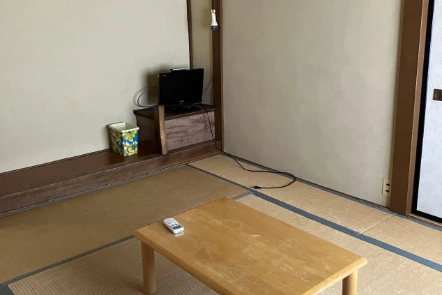 リゾートバイトの寮の部屋の中を撮影した画像。部屋には座卓とテレビが置かれており、床は畳が敷かれている。リゾートバイトの寮の部屋の画像。