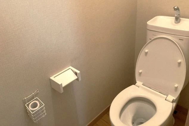 寮内のトイレ。清潔感のある白を基調とした空間で、手洗いタンク付きの洋式トイレが設置されています。