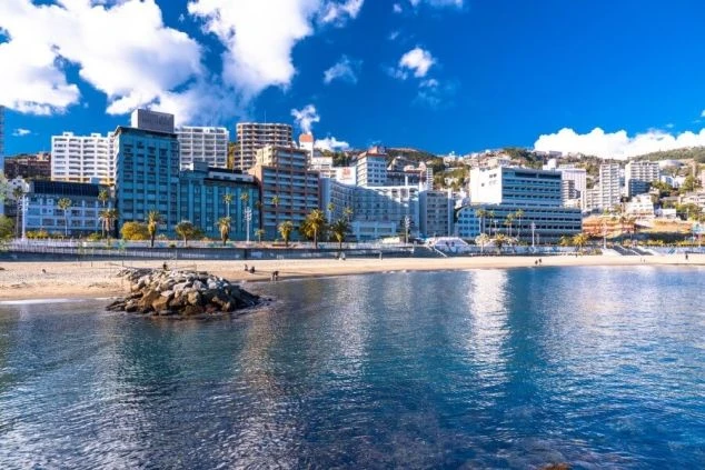 ビーチと高層ホテルが並ぶ熱海の海岸線の景色。晴れた日の熱海のイメージ。