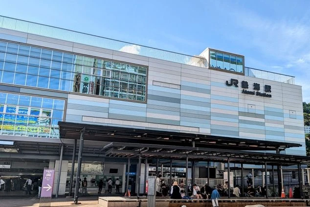 JR熱海駅の駅舎正面。近代的な外観と「JR熱海駅 Atami Station」の看板が見える。